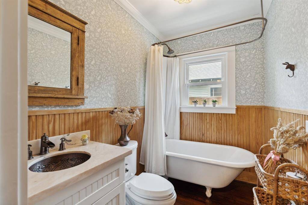 A shared full bathroom located on the first floor with wood accents and a stunning clawfoot tub.