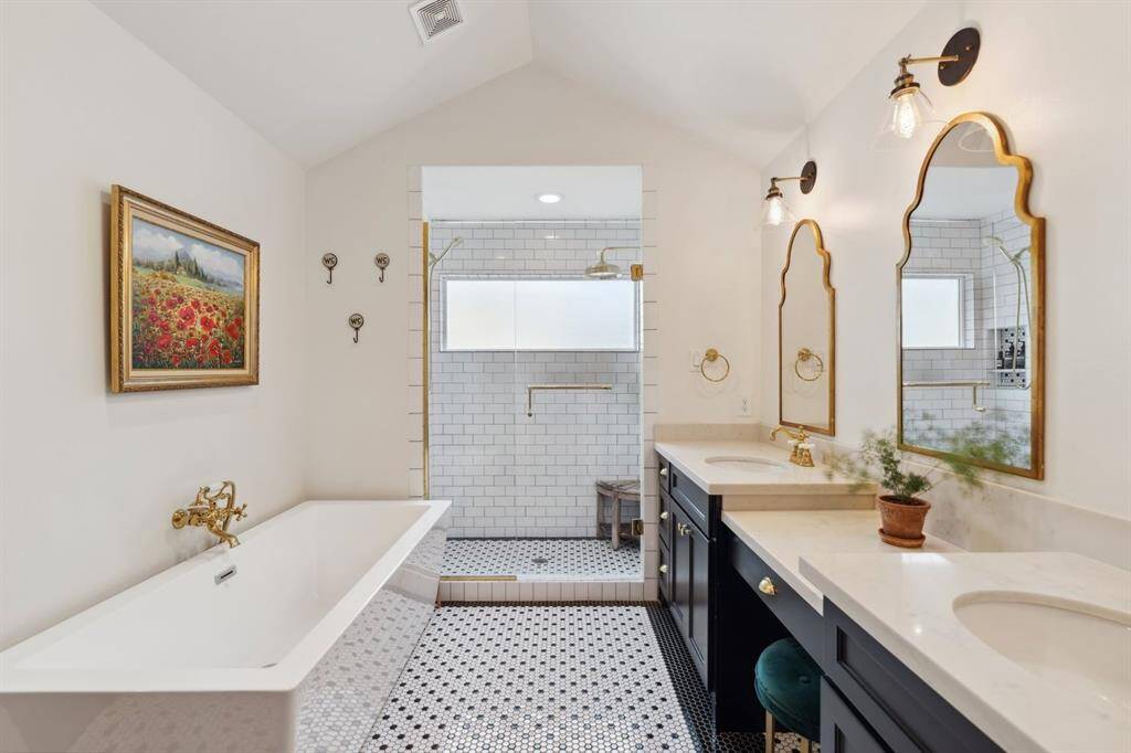 Luxurious primary bathroom with quartz countertops, dual sinks, vanity area, separate shower, soaking tub, and private water closet.