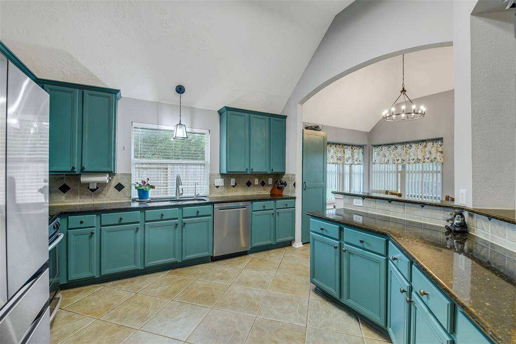 Another view of the kitchen with stainless steel appliances and breakfast bar.