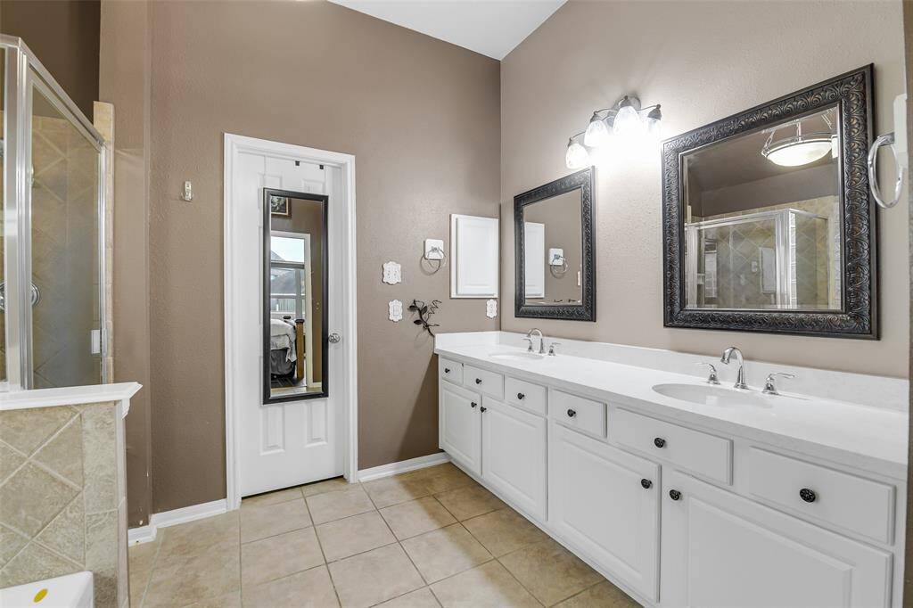 The primary bathroom has dual vanities, plenty of storage space, and a walk in closet.