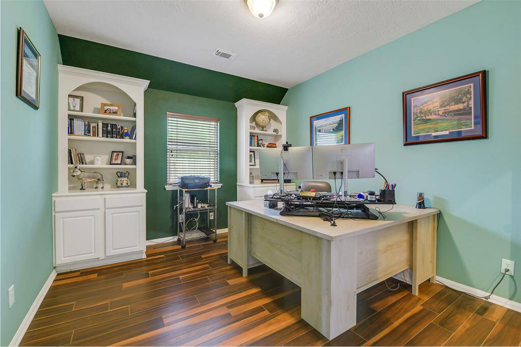 The office sits across from the dining room and includes custom built ins and French doors.