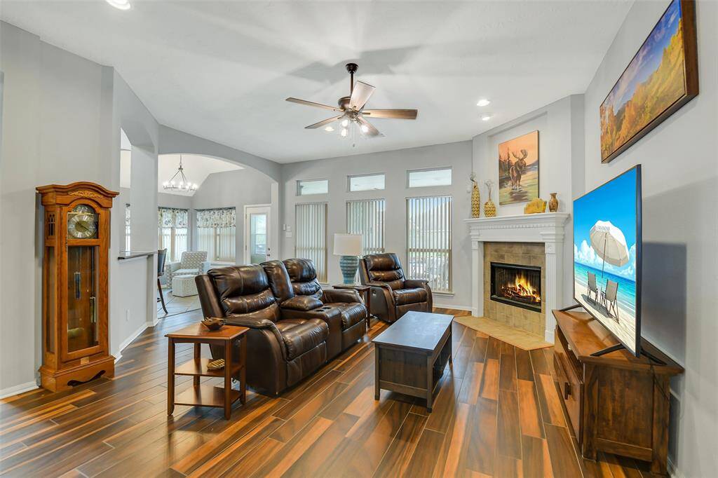 The living room with a cozy fireplace is open to the kitchen and dining areas, with great views of the pool and backyard.
