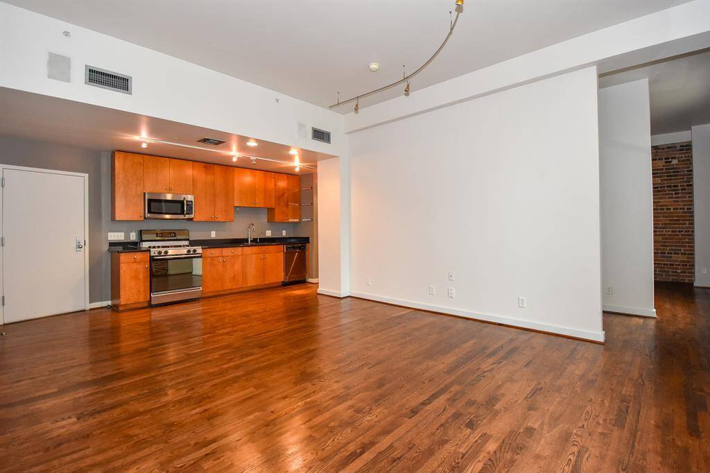Alternate angle showcases the kitchen's stylish design and connection to the living area. Enjoy modern finishes, generous counter space, and a breakfast bar that opens to a sunlit living room with skyline views.