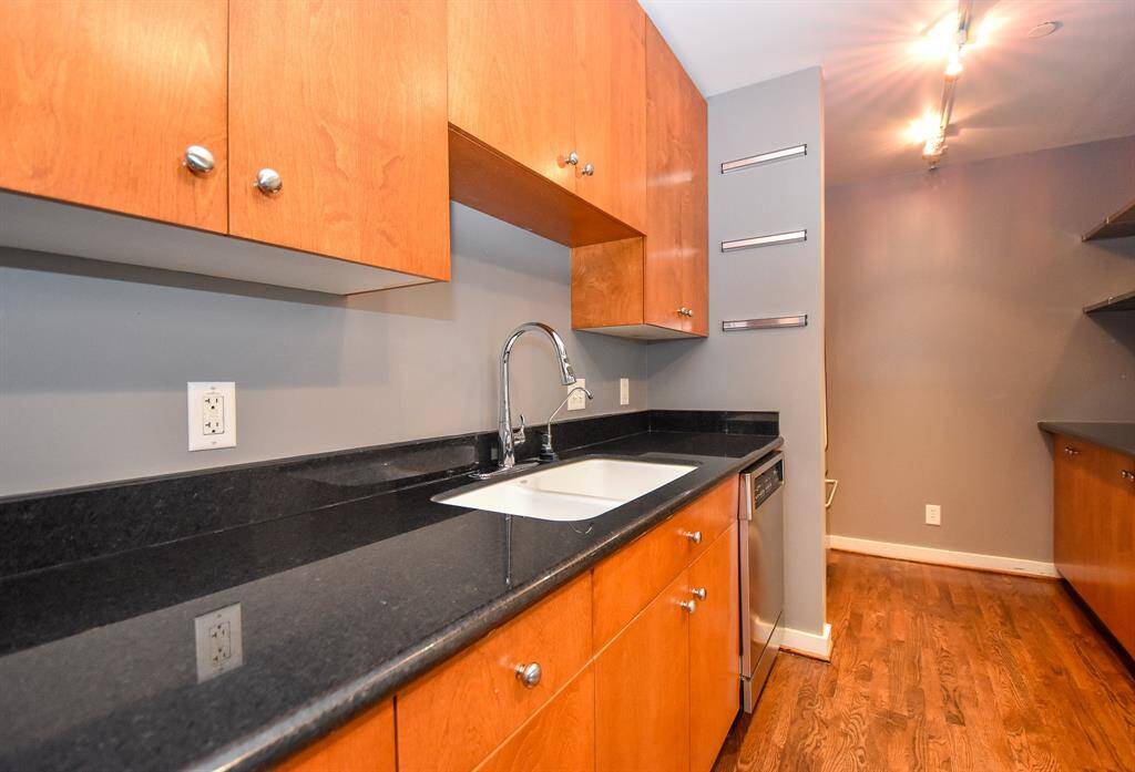 Another view of the kitchen showcasing the rich wood-colored cabinetry paired with sleek black countertops.
