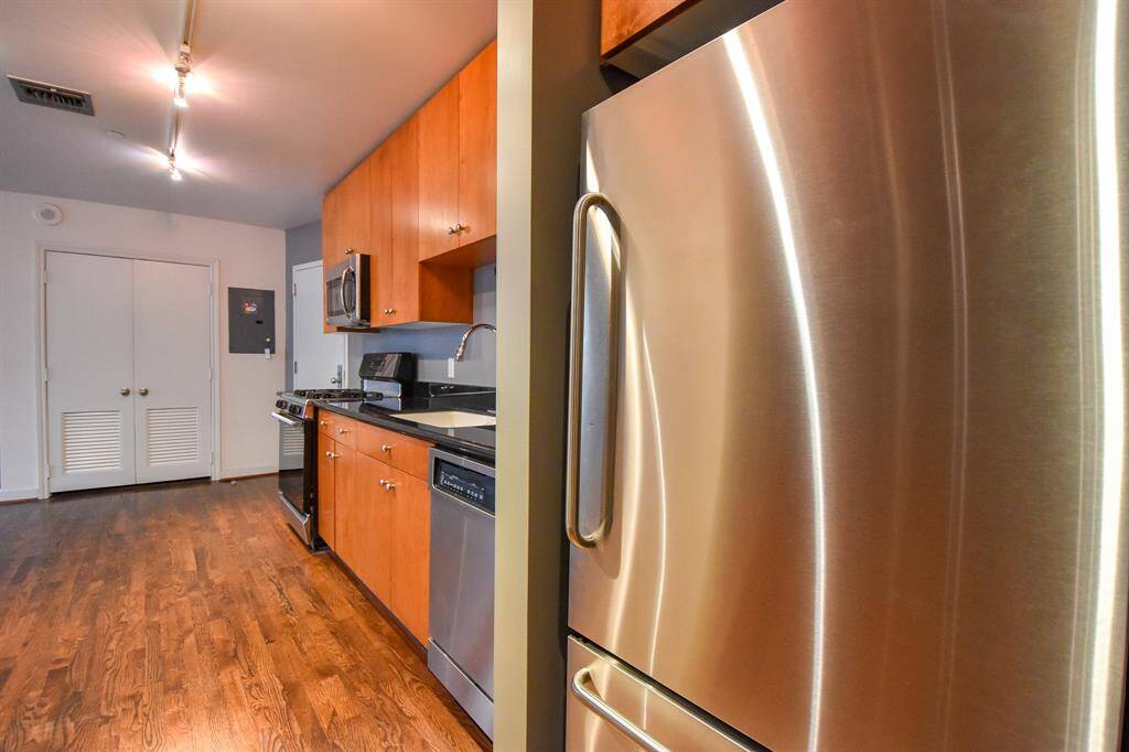 Another angle of the kitchen featuring a sleek stainless steel refrigerator, perfectly complementing the modern design.