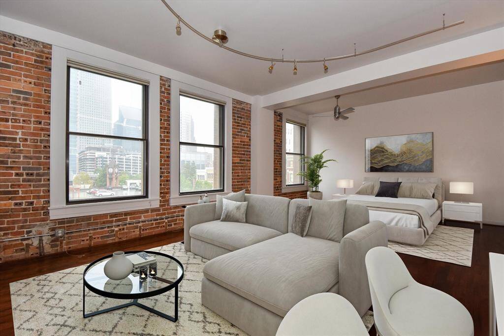 Enjoy stunning skyline views from this stylish open-concept loft, featuring exposed brick walls, oversized windows for a perfect blend of charm and comfort at Bayou Lofts. (Furniture is virtually staged) #bayoulofts #4A