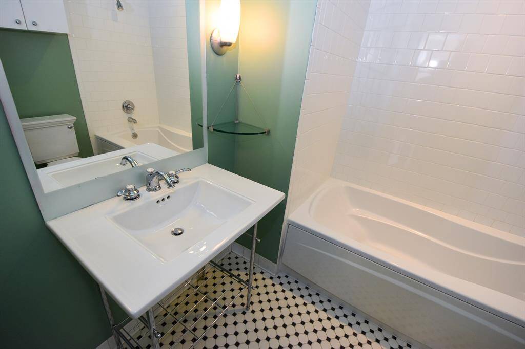 The second bathroom features a stylish sink and a luxurious soaking tub, offering a relaxing retreat.