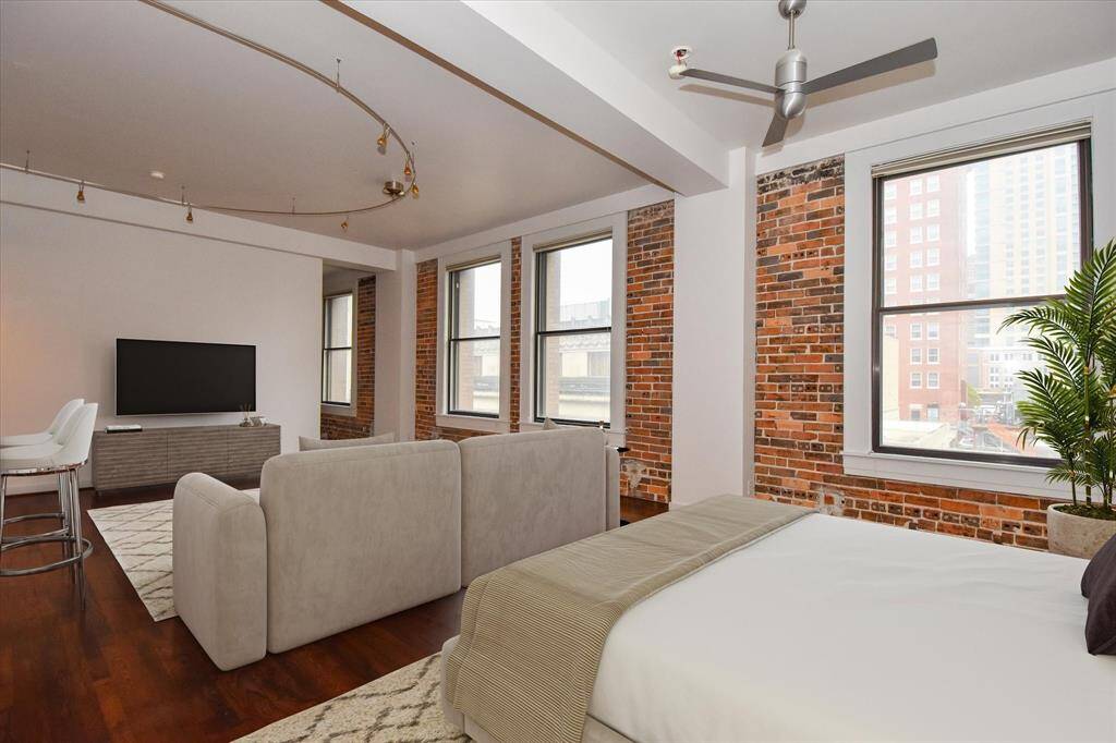 This spacious living room is filled with natural light from large windows that frame breathtaking views of downtown. A perfect space to relax or entertain with an unbeatable urban backdrop.