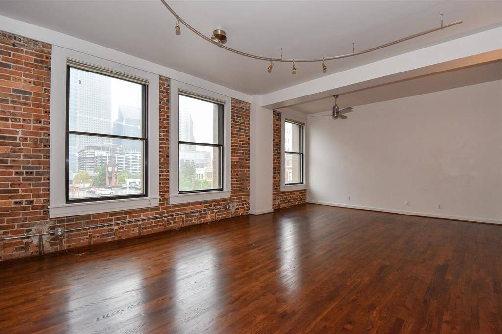 Alternate view of the living area highlights the open layout and beautiful hardwood floors, with expansive windows framing vibrant downtown views and flooding the space with natural light.
