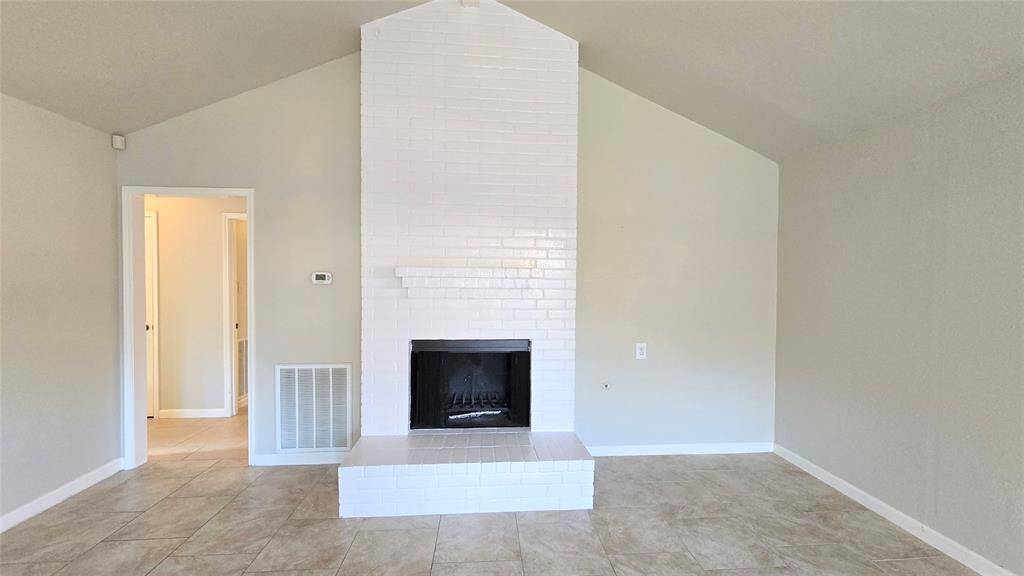 This large, spacious den with vaulted ceilings and a stunning brick fireplace is the perfect spot to gather with loved ones or relax after a busy day.