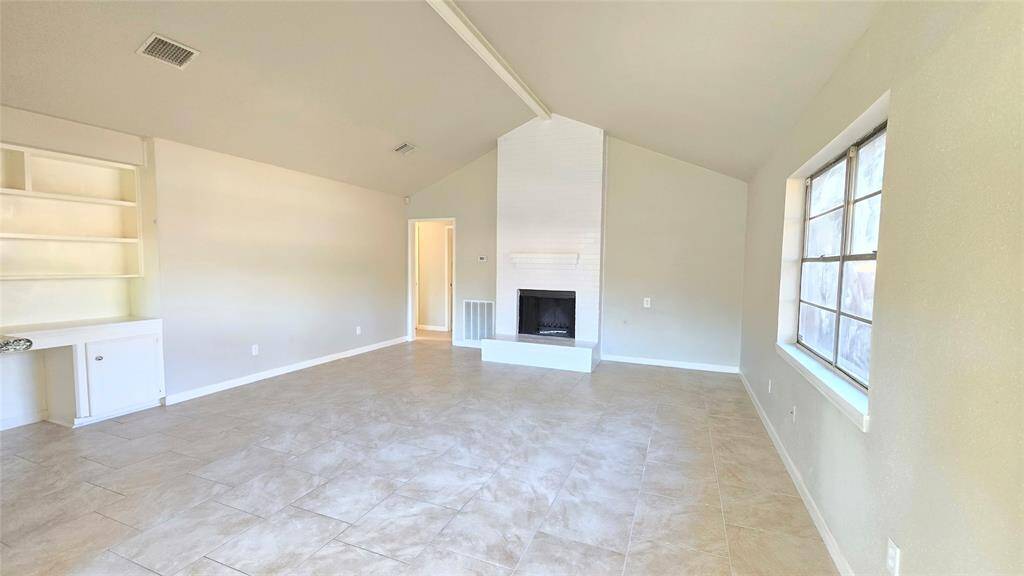 This large, spacious den with vaulted ceilings and a stunning brick fireplace is the perfect spot to gather with loved ones or relax after a busy day. The oversized mantle is ready to showcase your favorite decor or family photos, adding a personal touch to this cozy, welcoming space