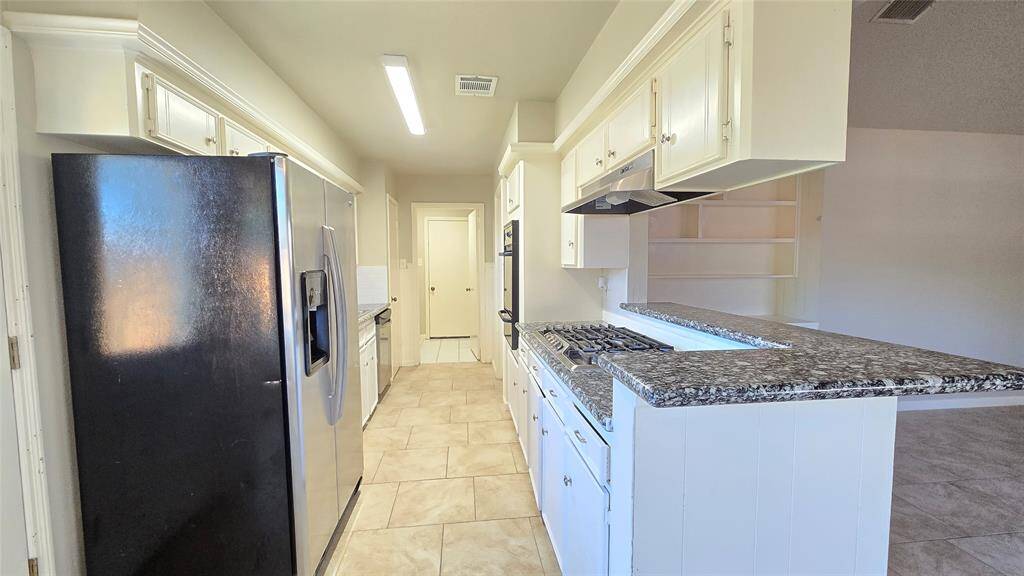 The updated kitchen features stainless steel appliances, including a refrigerator, built-in gas oven, and a 5-burner gas cooktop—perfect for cooking up your favorite meals in style.