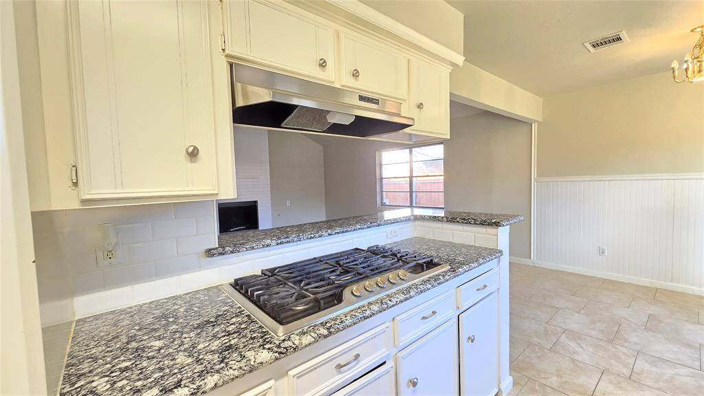 The 5-burner gas cooktop is the heart of this kitchen, surrounded by sleek cabinetry that offers both style and plenty of storage space for all your kitchen essentials.