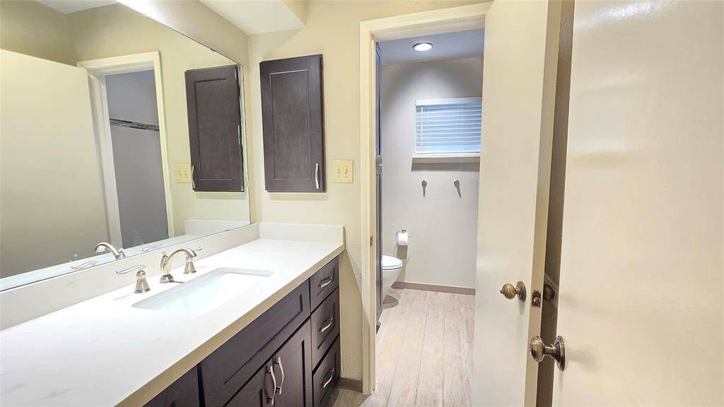 This remodeled hall bathroom features separate compartments—one for the toilet and bathing area, and another for the sink—making it perfect for convenient sharing and added privacy.