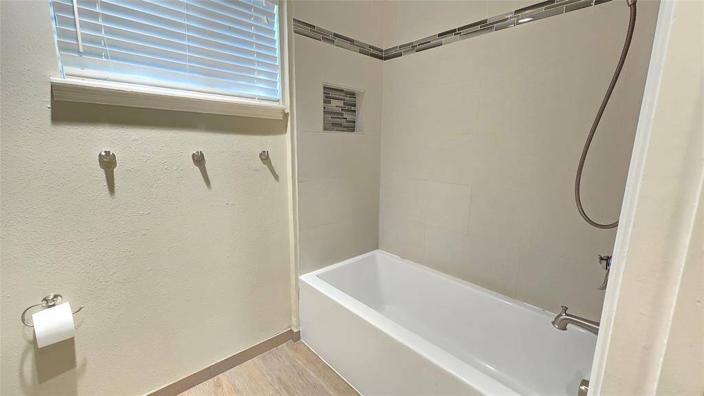 This bathroom features a tub and shower combo, offering the perfect blend of relaxation and convenience, making it ideal for both quick showers and leisurely baths.