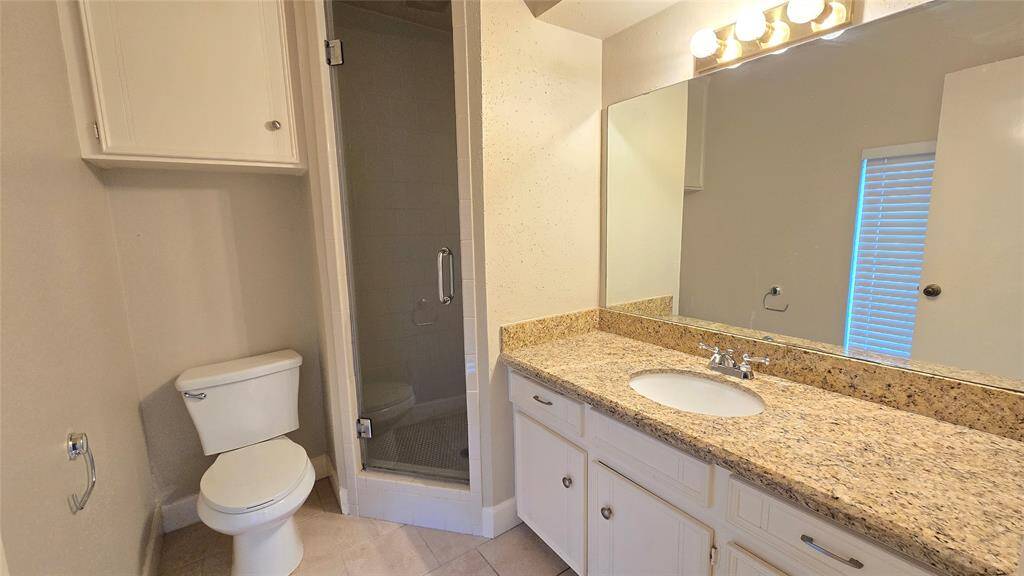 The attached owner’s bathroom features sleek granite counters, a spacious shower, and convenient over-the-toilet storage for added functionality.