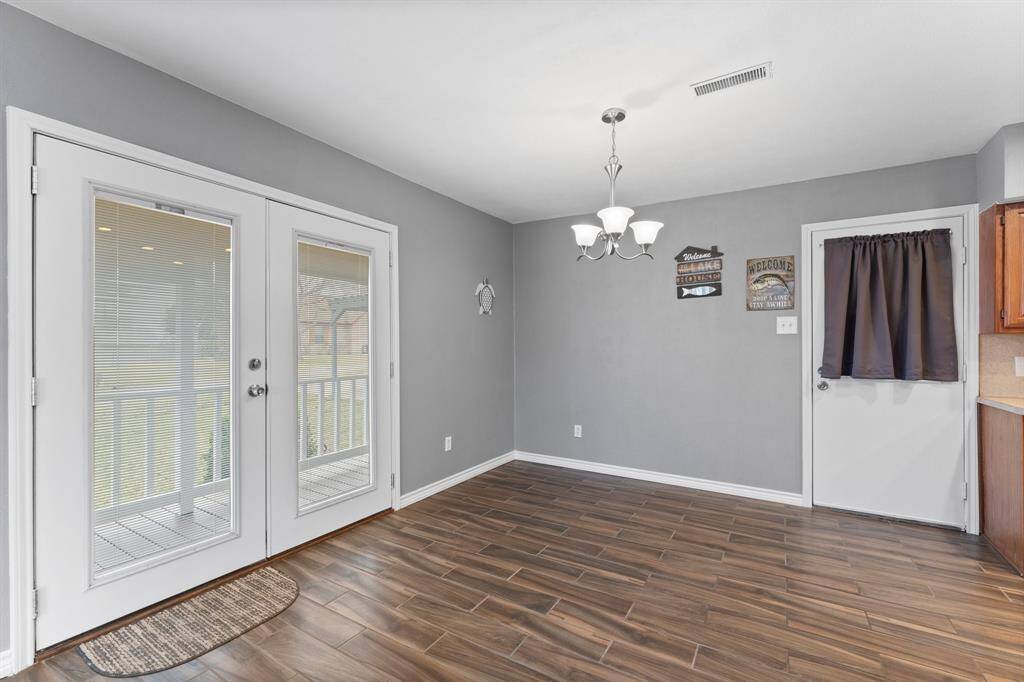 The open layout of the living area flows into a dining area. French doors provide natural light and access to the outdoors.