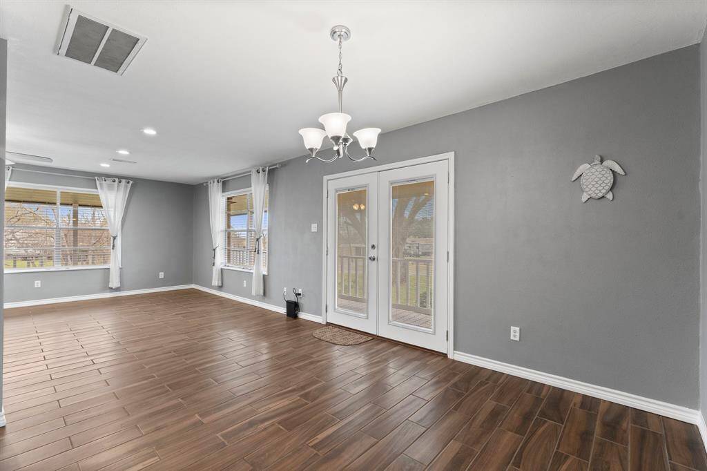 Bright dining area with modern light fixtures. Features French doors leading to a porch.