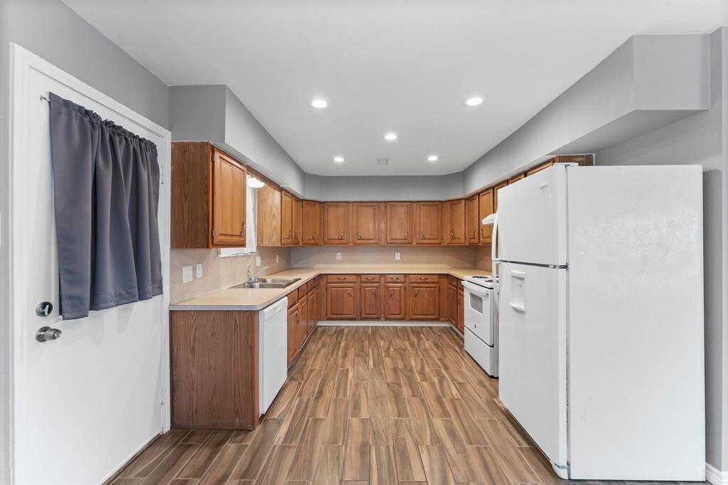 This spacious open-concept area features a kitchen with ample wooden cabinetry, modern lighting, and appliances. The living space has large windows, providing a bright and welcoming atmosphere.