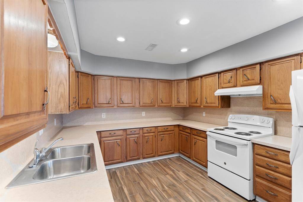 Spacious kitchen with wood cabinets, modern appliances, and wood-look flooring. Ample counter space and recessed lighting enhance functionality.