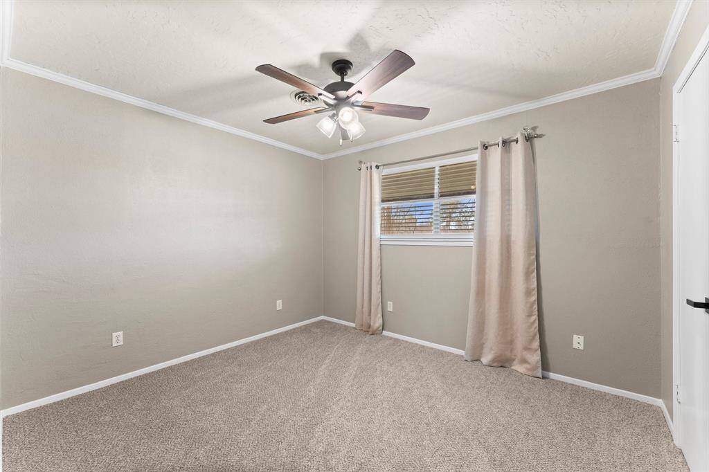 This room features neutral walls and carpet, providing a cozy and versatile space. It includes a ceiling fan with lights, offering comfort and illumination.