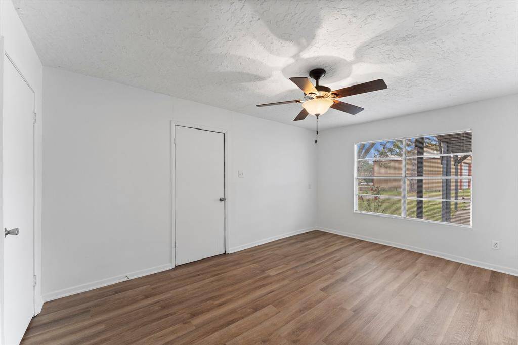This room features fresh white walls, wood-style flooring, and a ceiling fan for comfort. It includes convenient access to a laundry area with a washer and dryer.