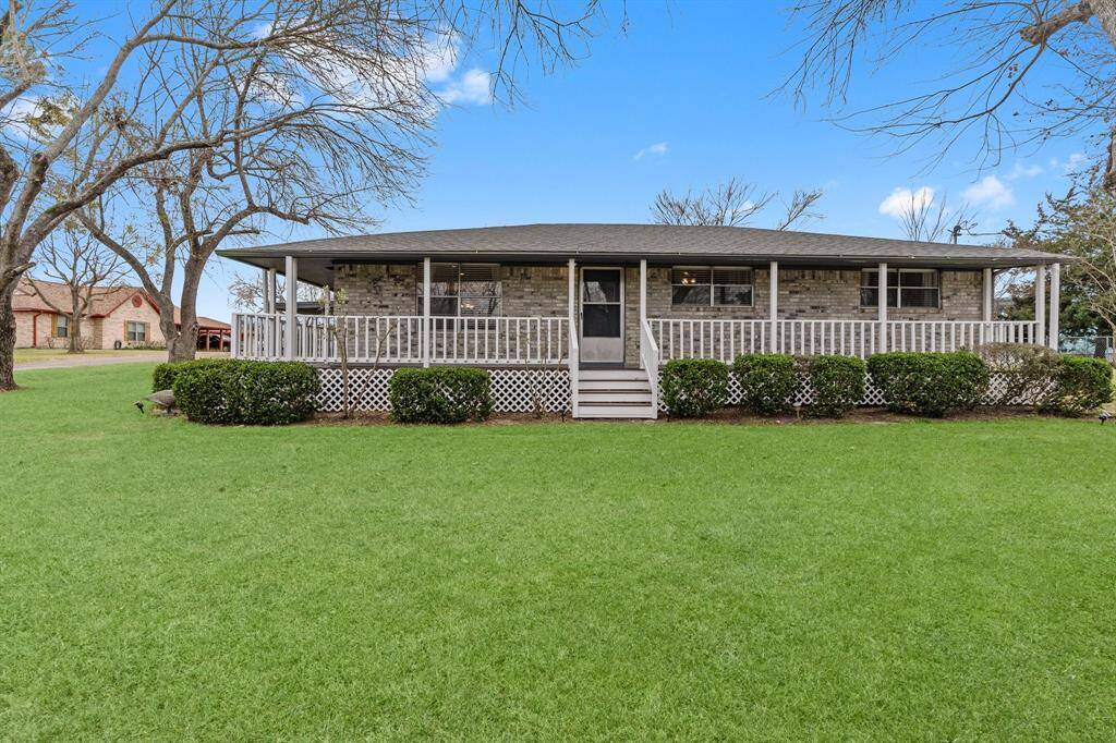 This charming home features a spacious front yard with mature trees and a large wrap-around porch offering a welcoming and serene setting, ideal for relaxation.