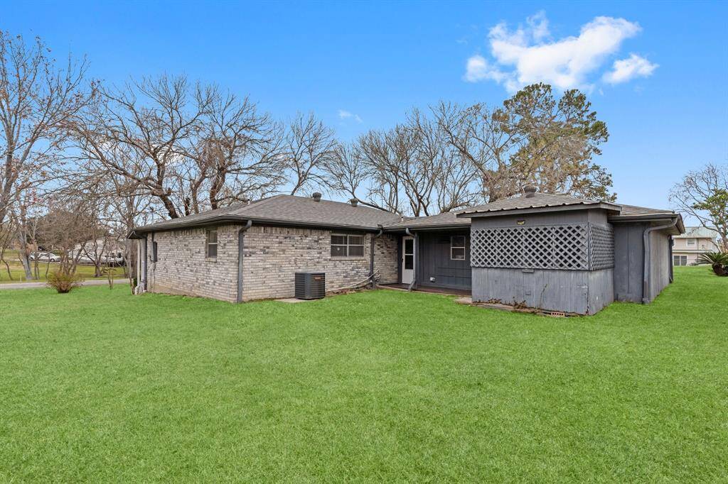 The yard is enclosed by a chain-link fence and features a wooden shed, surrounded by trees, offering ample storage space.