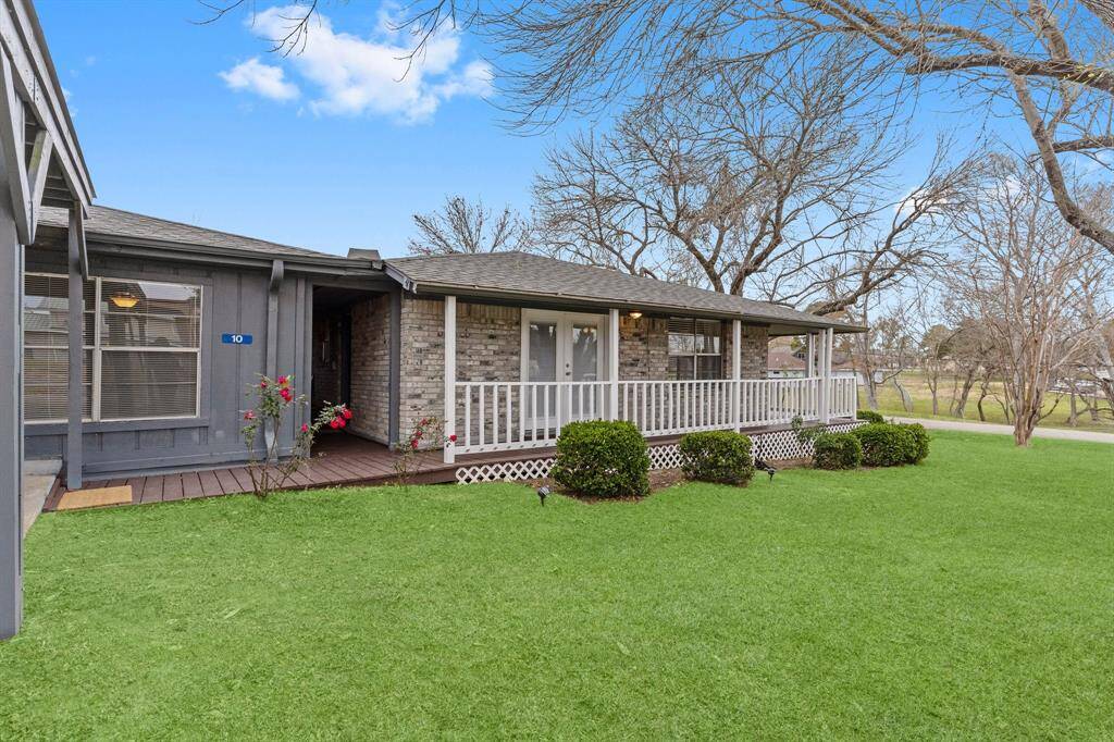 This photo shows a single-story brick home with a spacious backyard with a small covered patio area. The yard is well-maintained and surrounded by mature trees, offering a serene outdoor space.