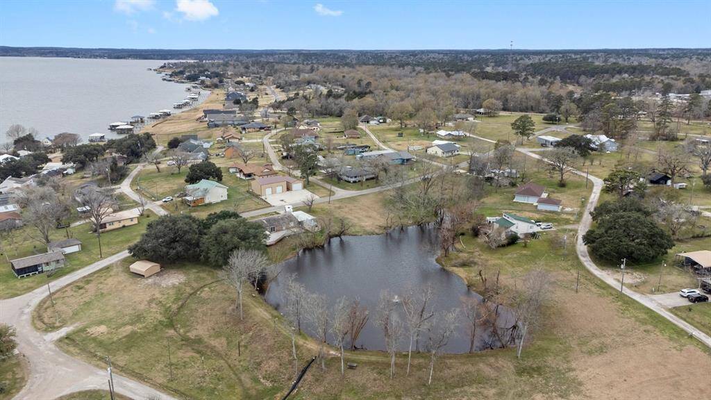 This aerial photo showcases a lakeside community. A small pond is visible in the foreground, adding to the scenic landscape. The area offers proximity to the lake, providing potential for waterfront activities and a peaceful residential setting.