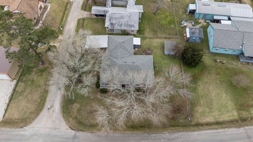 This aerial photo showcases the large yard on a corner lot. The property has mature trees and a driveway with a carport.