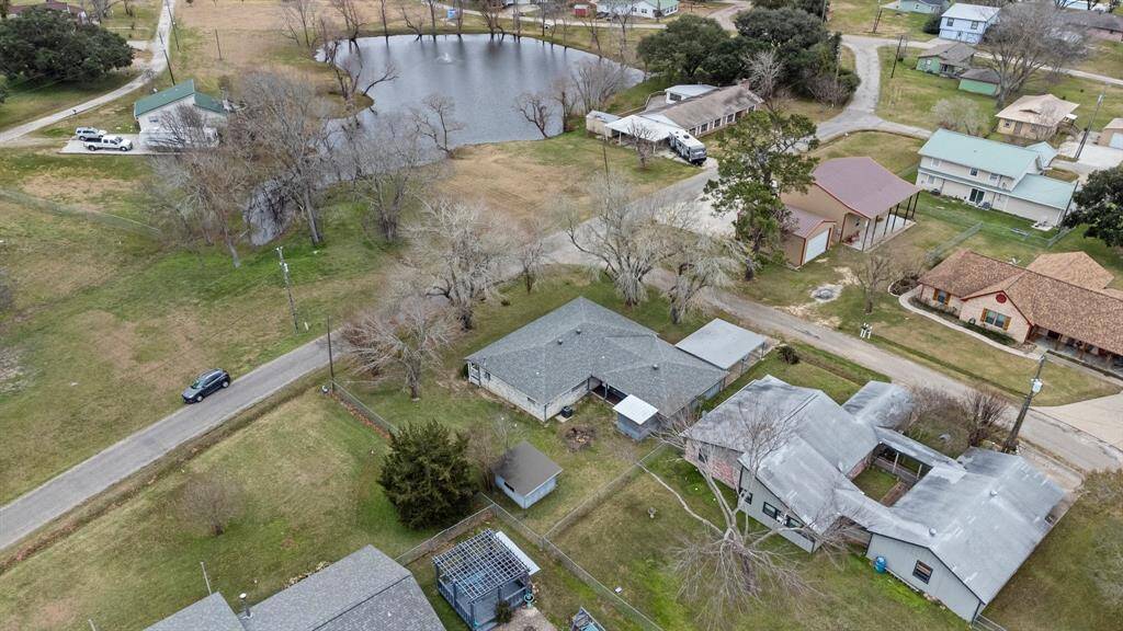 This aerial photo showcases the home and there is a small pond surrounded by trees, providing a natural setting.