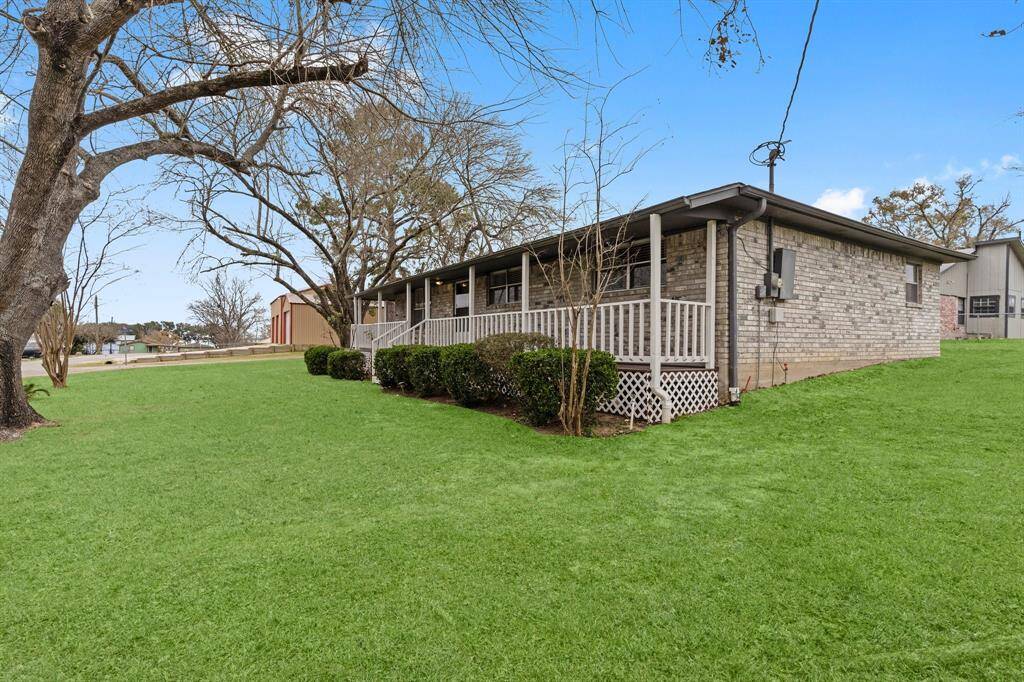 Single-story brick home with a welcoming wrap-around porch, nestled on a spacious, well-maintained lawn.