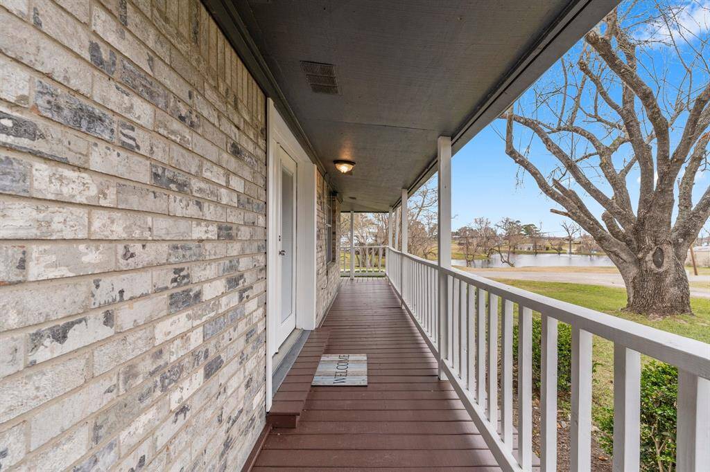 This photo showcases the welcoming front porch and offers a serene view of a large tree and a nearby pond, perfect for relaxing outdoors.