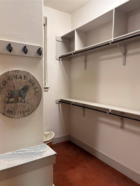 This primary closet is massive. This picture shows 1/4 of the storage and hanging space available. This primary closet contains hanging rods for long and short clothes, open shelving, built in dresser, a bench topped with granite for putting on shoes, and two windows.