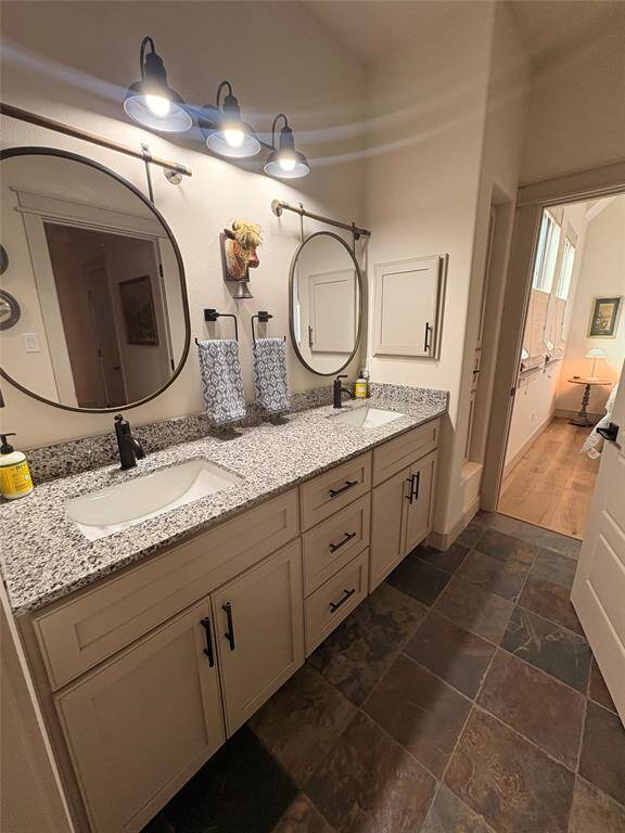 Between the upstairs bedrooms is a large bathroom. It has custom cabinetry with soft close drawers and cabinets, a built in cabinet for bathroom supplies, two sinks with medicine cabinets, pretty granite and fixtures, and two cute mirrors.
