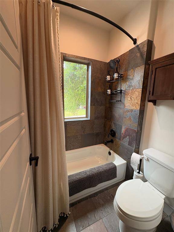 In a separate room you have a toilet area and a shower bath combo. The flooring and tile surround is a pretty slate.