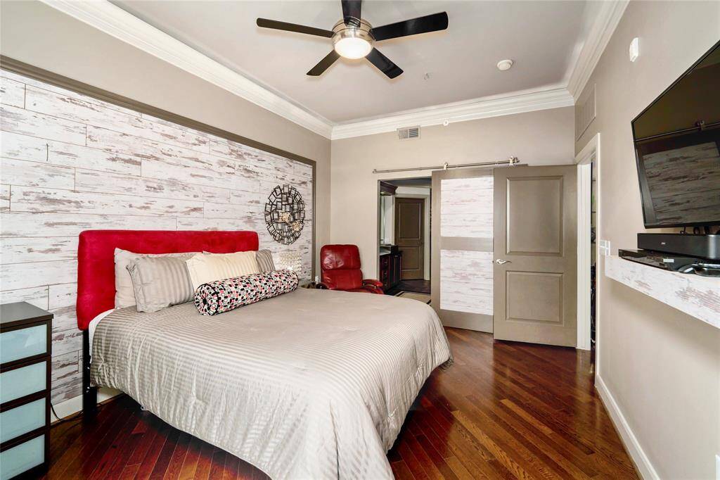 Reverse view of the primary bedroom with horizontal custom hardwoods and the entrance to the primary bath.