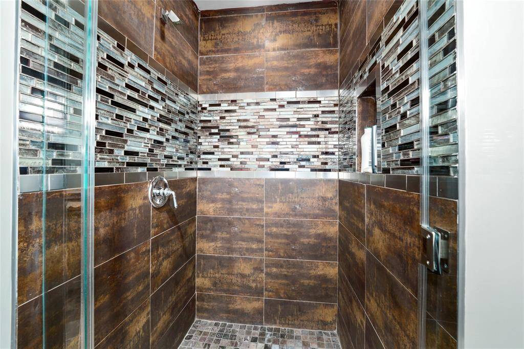 Closer look at the primary stand-up shower with a recessed shelf for toiletries.