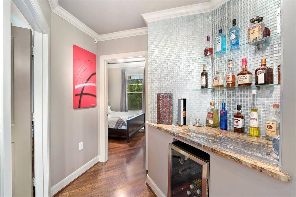 Just down the hallway to the left is your custom bar with a fridge. Plenty of shelving for entertaining. Hallway full bath and secondary bedroom.