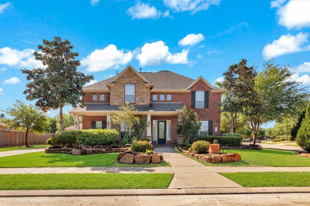 This is a charming two-story home with a well-maintained front yard, featuring landscaped gardens and mature trees. The house has a welcoming porch and large windows, offering a bright and inviting exterior.