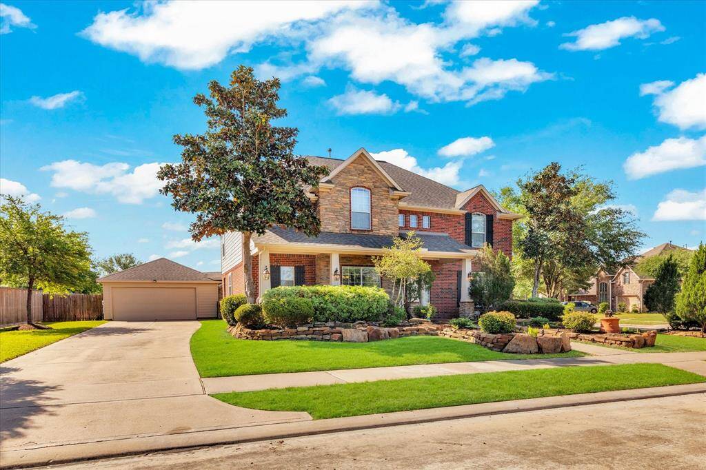 Formel model home with a well-manicured lawn and mature trees. The property features a spacious driveway leading to a detached garage, and attractive landscaping enhances its curb appeal.