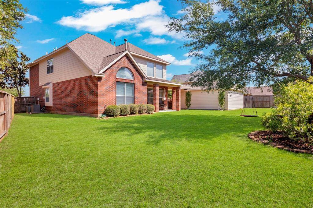 Features a patio area, lush lawn, mature trees, and a swing, perfect for outdoor activities and relaxation.