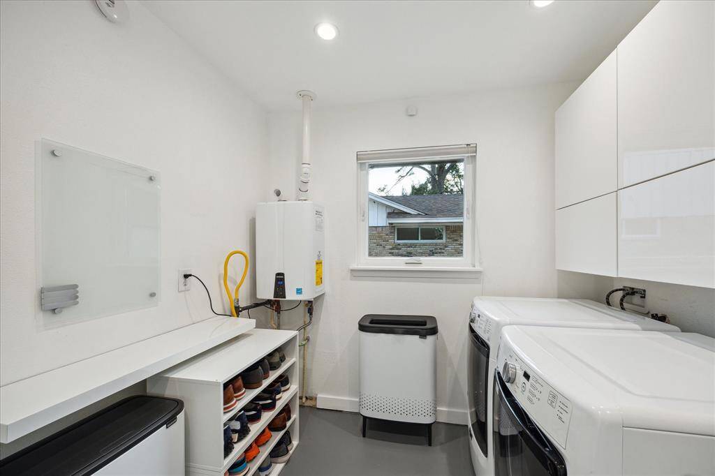 Laundry room with recent energy efficient gas tankless water heater and plenty of cabinets is located off the kitchen