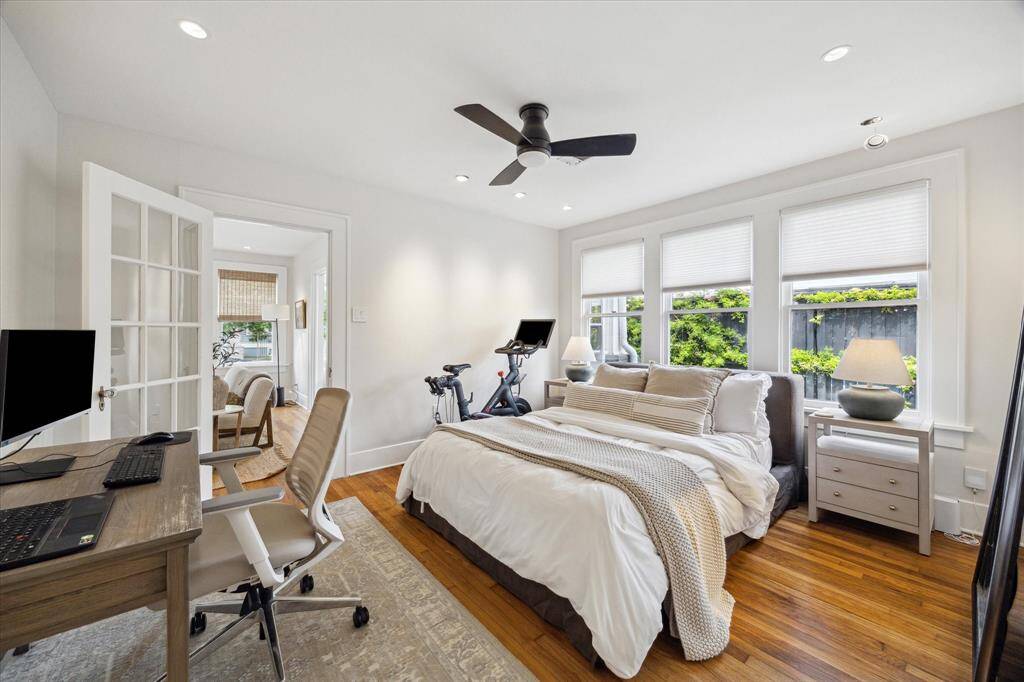 Bright, cozy secondary bedroom with hardwood floors and large windows offering plenty of natural light. Adjacent sitting room with French doors enhances the space.