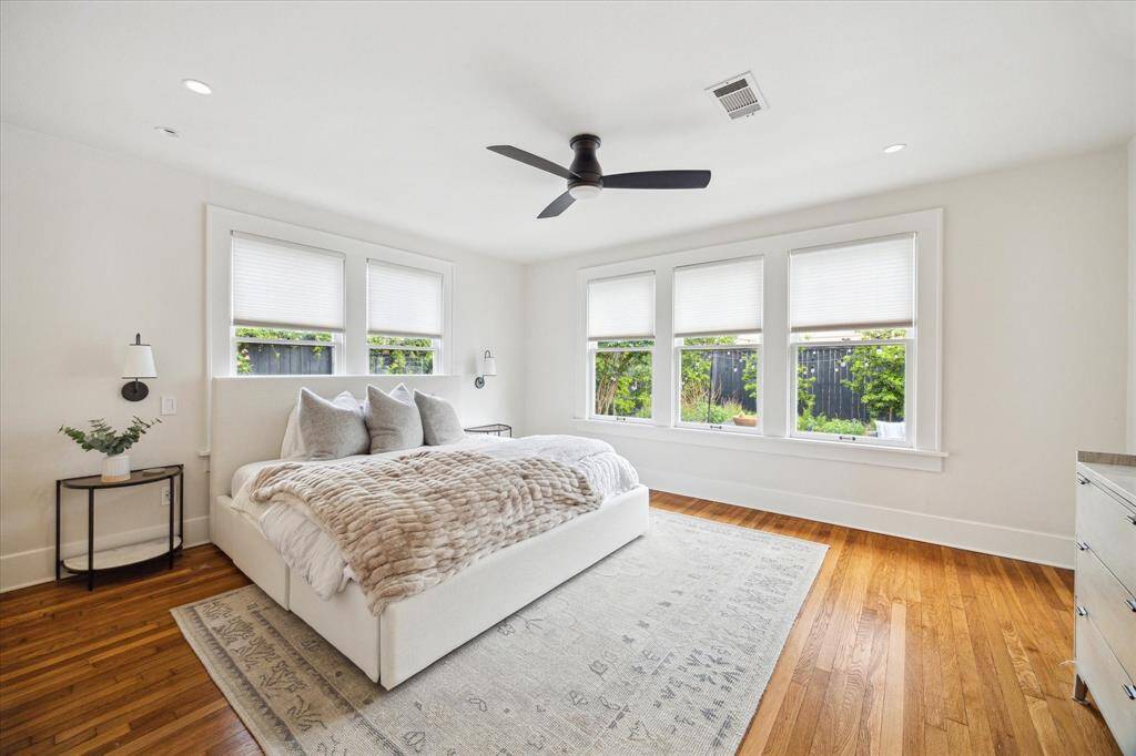 Spacious primary bedroom with hardwood floors, large windows, and a neutral color palette, creating a serene atmosphere.