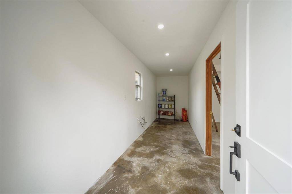 Garage has possibilities as a versatile room with a high ceiling and wooden ladder leading to a loft area. The space is ideal for a workshop or creative studio.