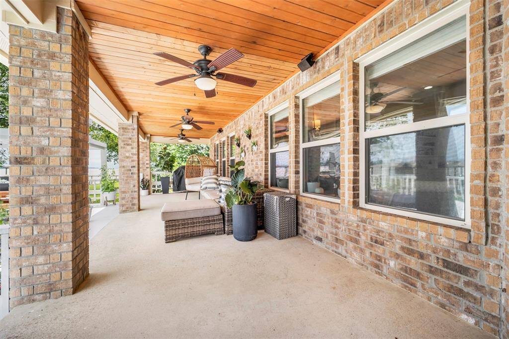 Enjoy the outdoors in comfort on your covered porch, featuring a warm wood-paneled ceiling and ceiling fans for a breezy, shaded retreat