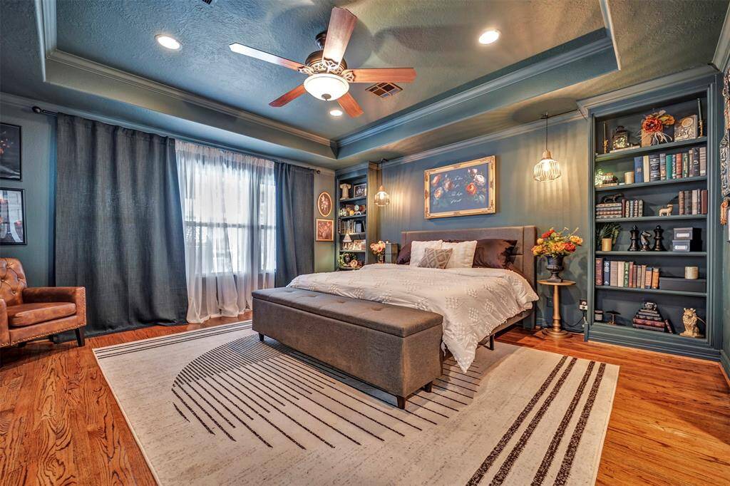 Spacious primary bedroom features moody tones that create a cozy and inviting atmosphere, includes the original hardwood floors that add warmth and character. (Please Note: Seller happy to accommodate buyer's if neutral or lighter paint desired for primary suite)