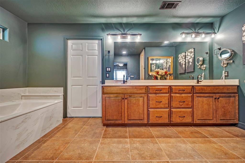 Oversized primary bathroom includes double sinks, garden tub, & shower